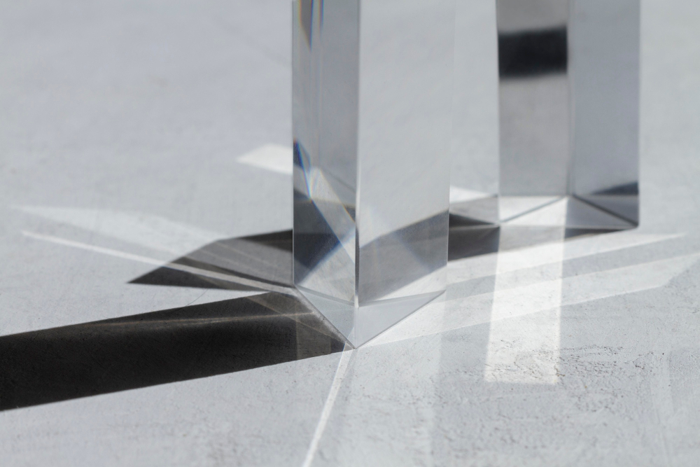 Close-up of glass prisms casting geometric light patterns on a textured surface.
