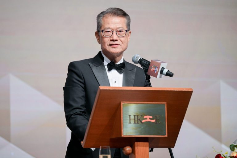 Man in tuxedo speaking at podium with HKIE logo