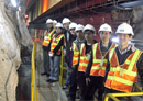 Construction workers in hard hats and safety vests standing in a tunnel.