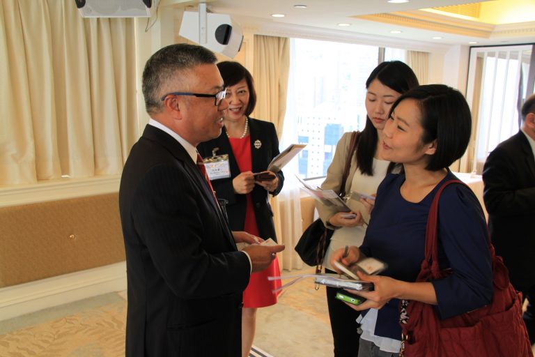 Business professionals exchanging materials at a networking event indoors.