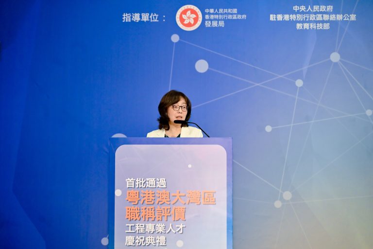 Woman speaking at podium during Guangdong-Hong Kong-Macao Bay Area engineering professionals title evaluation ceremony.