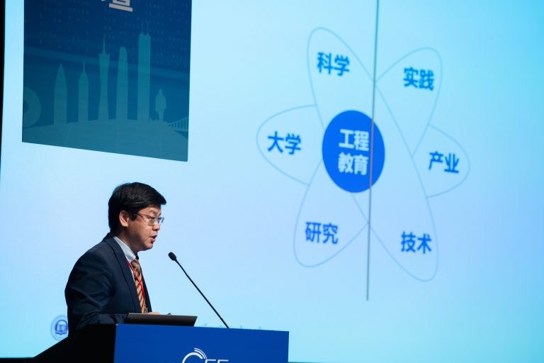 Man speaking at podium with presentation on engineering education and related fields.