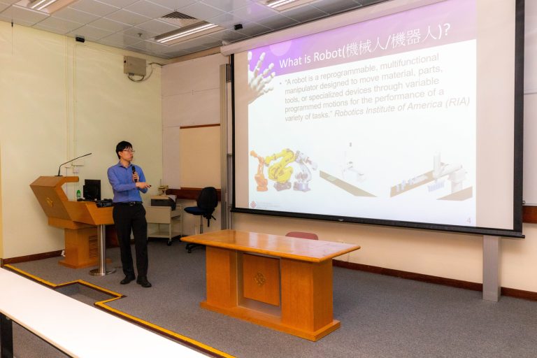 Speaker presenting robotics definition on screen in lecture hall