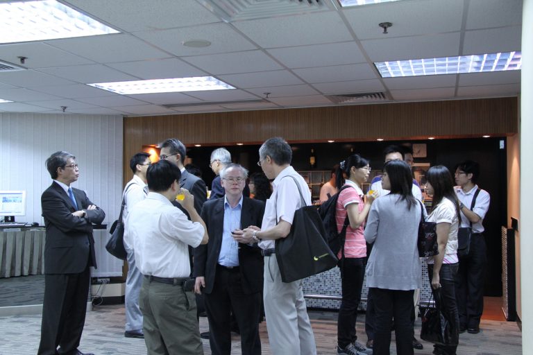 People networking at an indoor event, holding drinks and conversing in small groups.