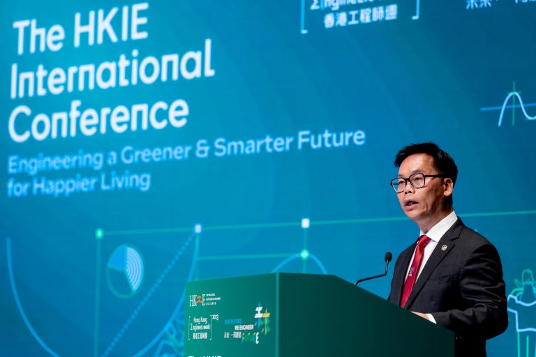 Man speaking at The HKIE International Conference podium with event branding.