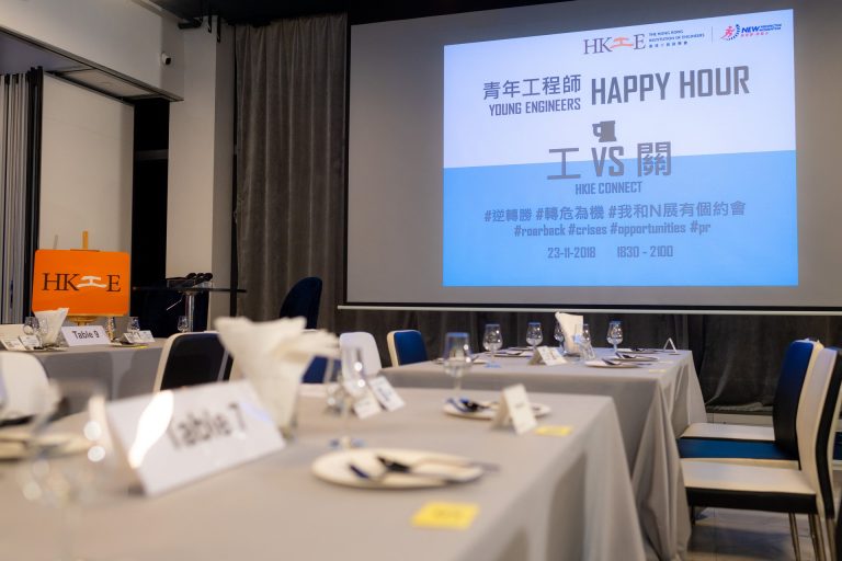 Young Engineers Happy Hour event setup with tables and presentation screen.