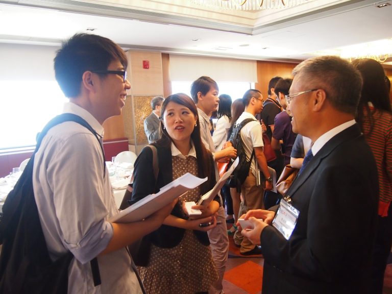 People networking at an event, smiling and exchanging business cards.