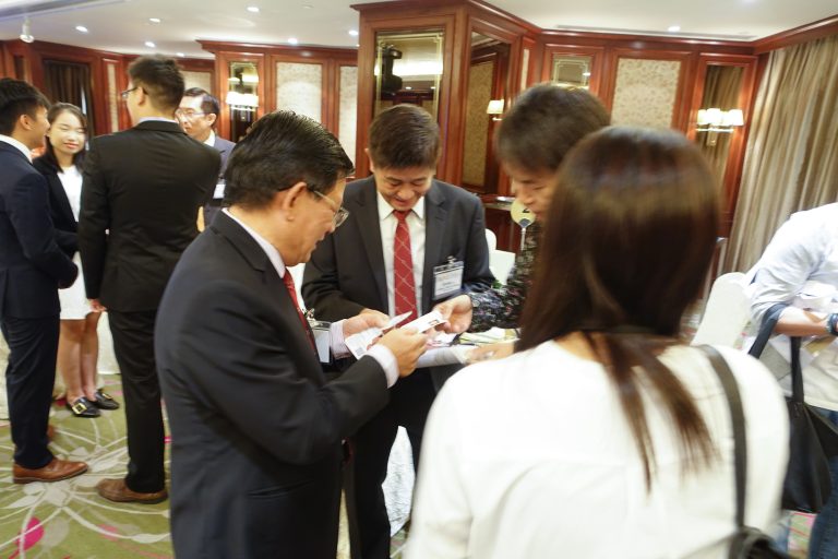 Business professionals exchanging documents in a formal indoor setting.