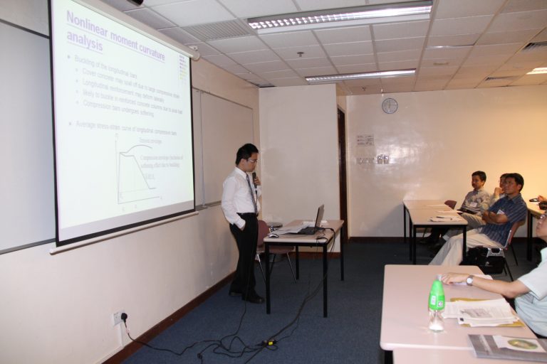 Engineer presenting nonlinear moment curvature analysis to an audience in a conference room.