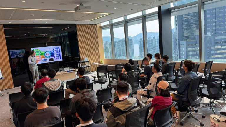Audience attending a presentation in a modern conference room with city views.