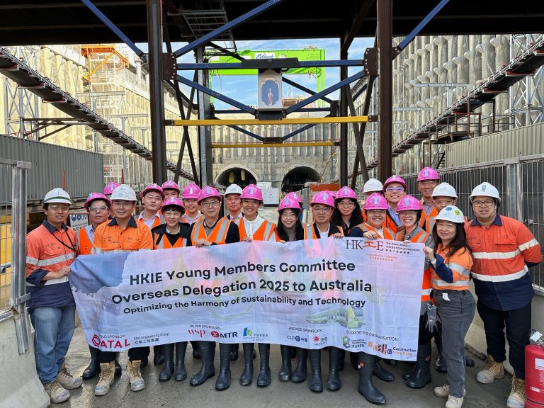 HKIE Young Members Committee delegation at construction site holding banner for 2025 Australia trip.