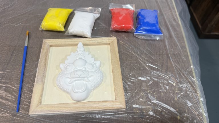 Painting kit with lion head sculpture, brushes, and colored powders in bags.