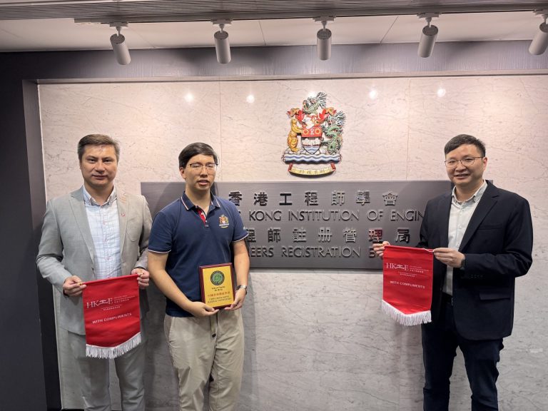 Three men pose in front of Hong Kong Institution of Engineers signage, holding red banners and a plaque.