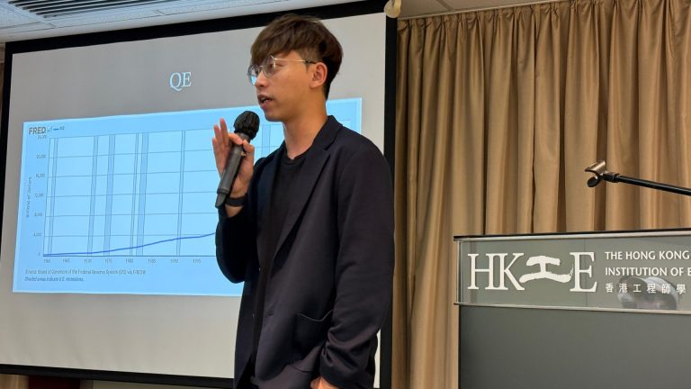 Speaker presenting M2 money supply chart at Hong Kong Institution of Engineers event.